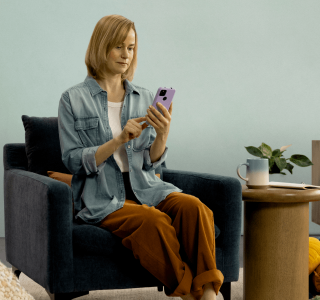 Woman sitting on a chair looking at her smartphone using the Rejoyn app
