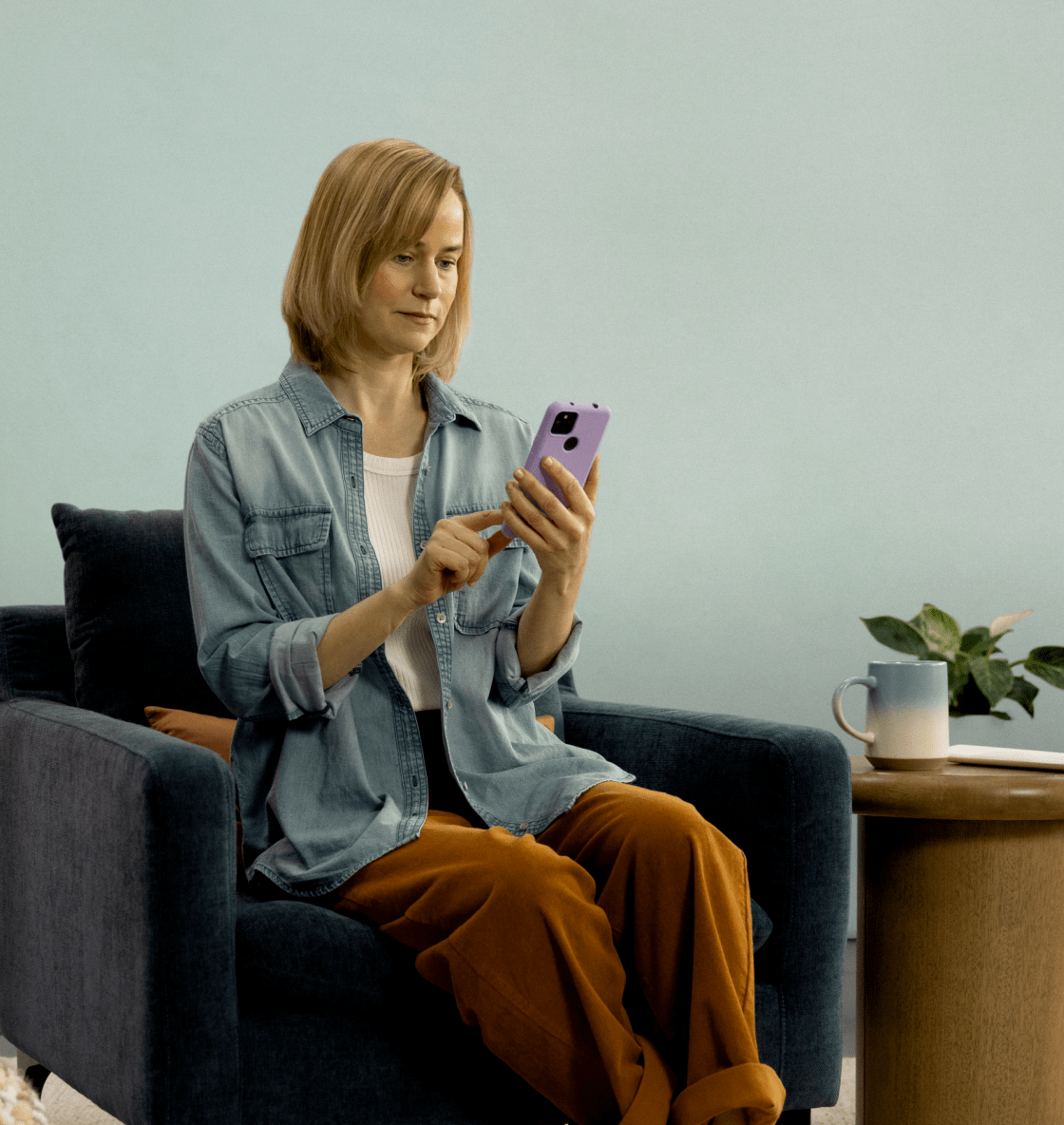 Woman sitting on a chair looking at her smartphone using the Rejoyn app